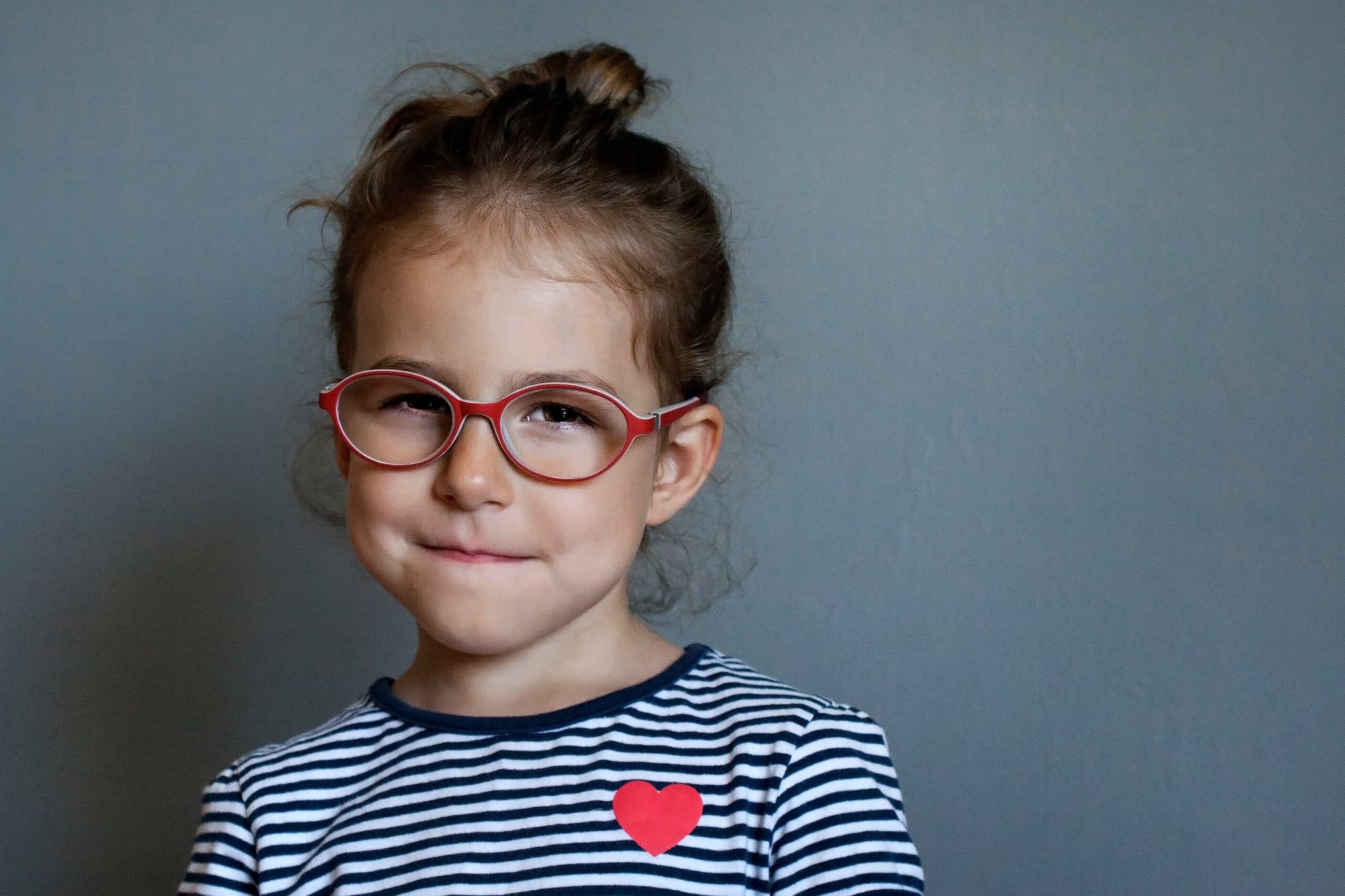 A little girl with red glasses. A child with a smirk