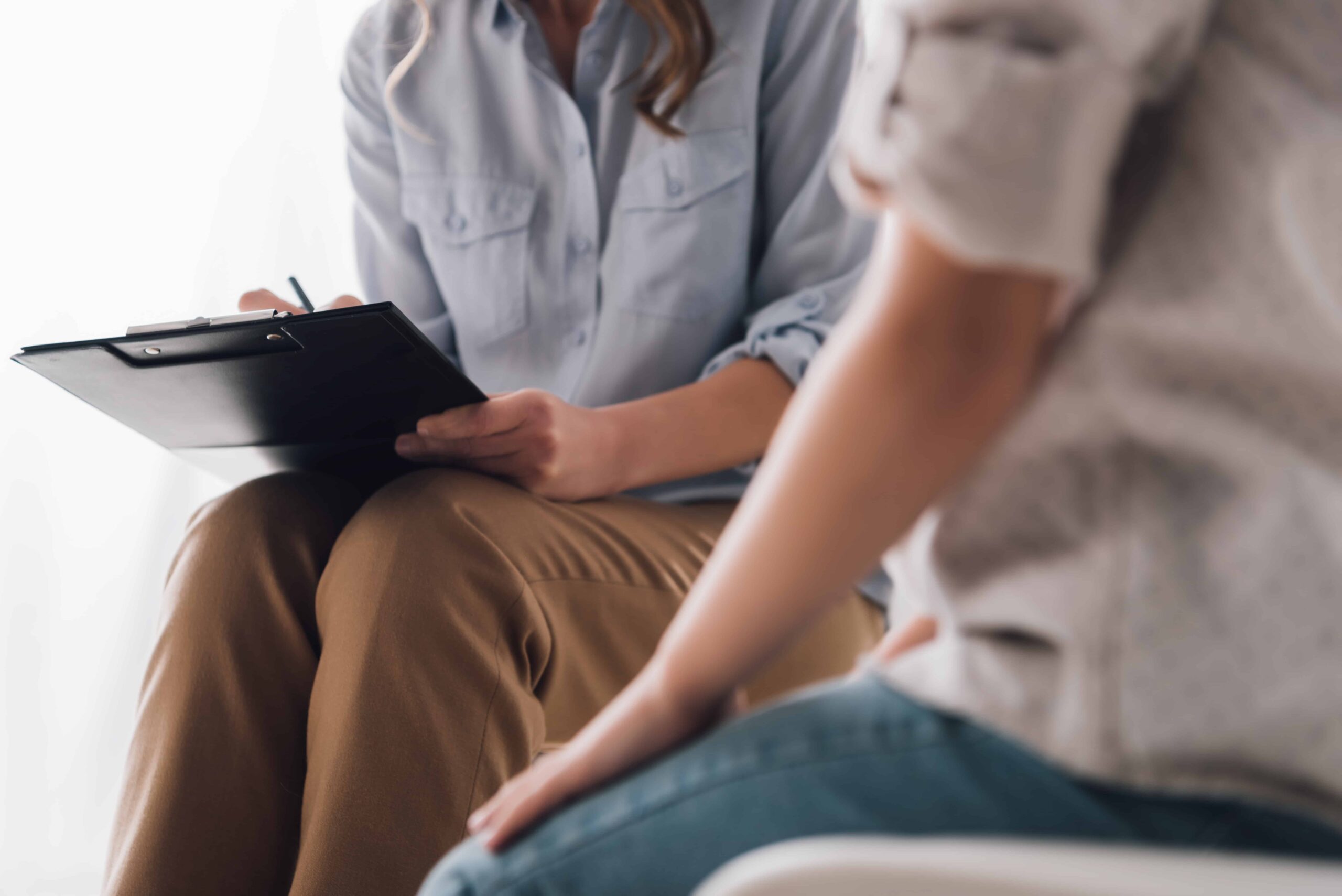 cropped shot of psychologist with clipboard sitting in front of