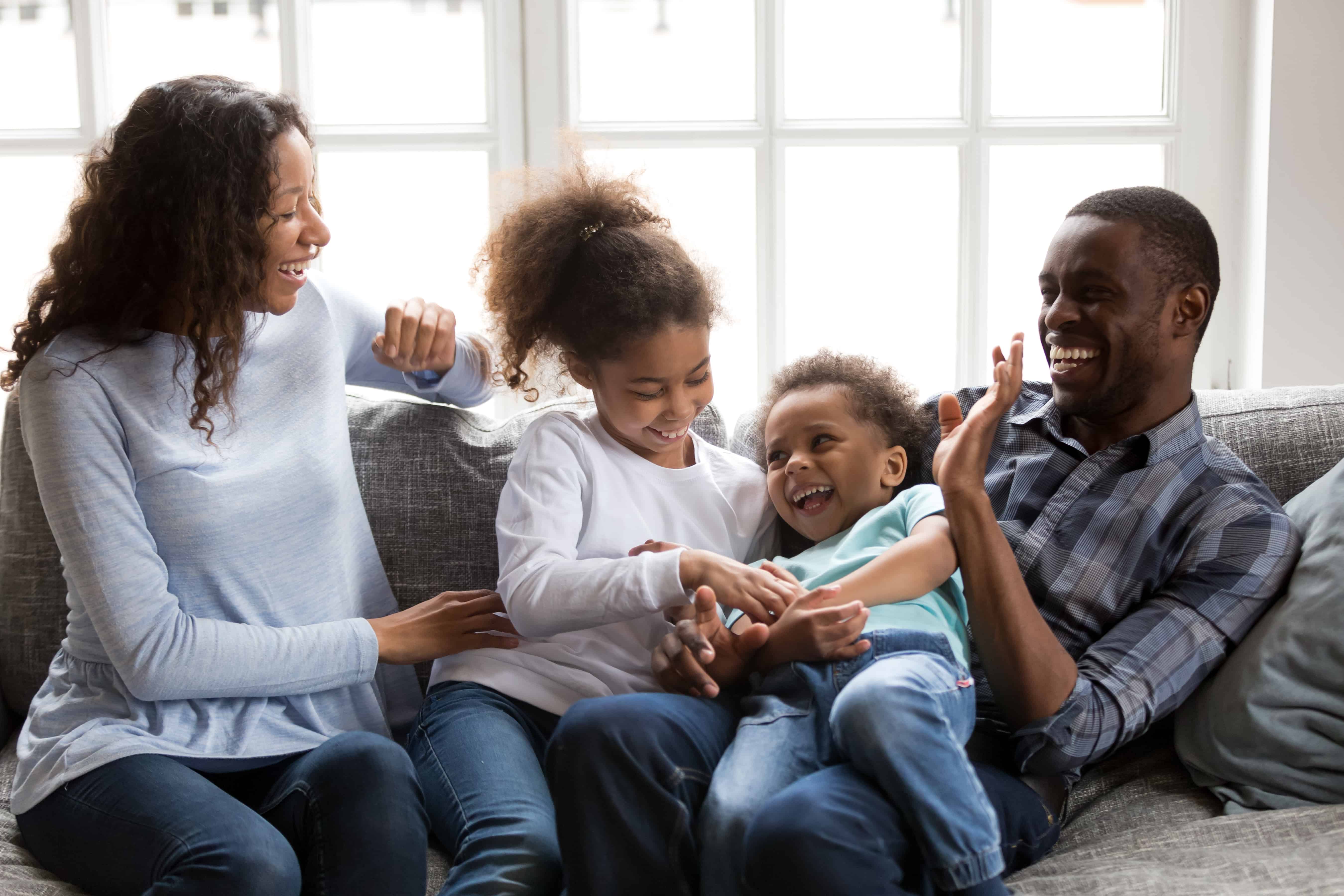 Happy black family laughing playing tickling children at home autism sibling