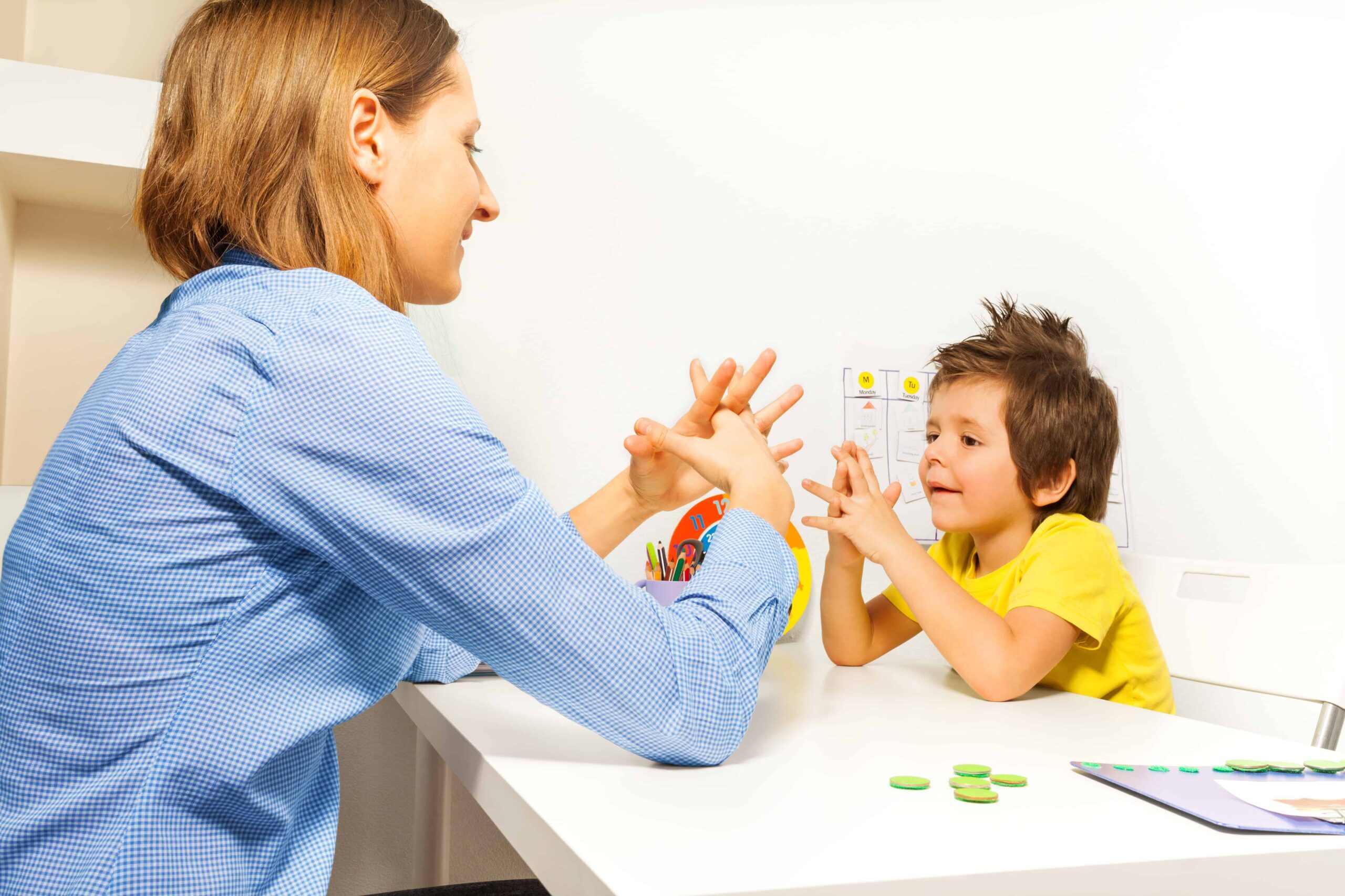 Boy exercises putting fingers with therapist