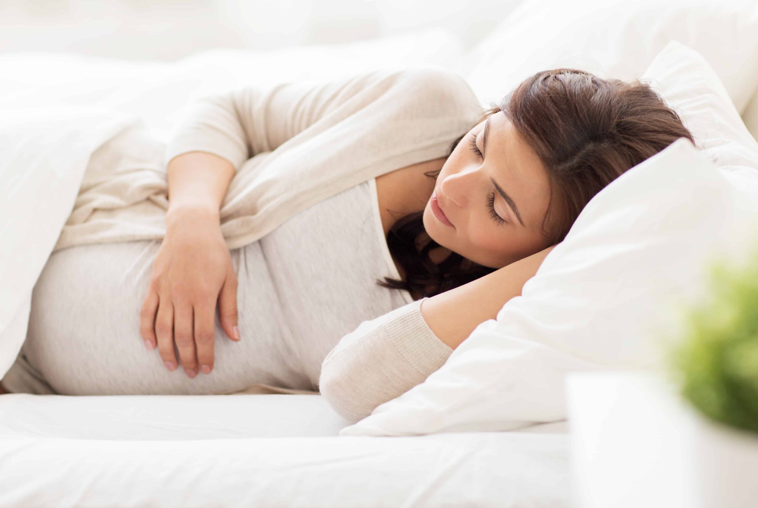 happy pregnant woman sleeping in bed at home